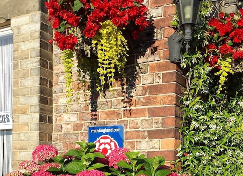Barbican House in York, brick exterior with hanging flower baskets and pink hydrangeas