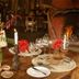 Crater Forest Tented Camp, Karatu: candlelit dining table with floral centerpiece beside a fireplace