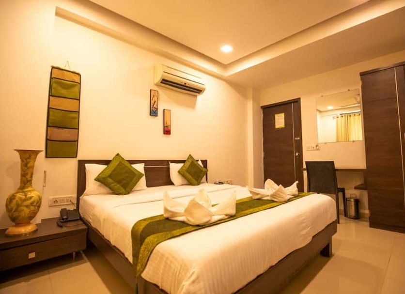 Hotel Shrimad Residency Ahmedabad guest room with double bed, wardrobe, mirror, and warm lighting