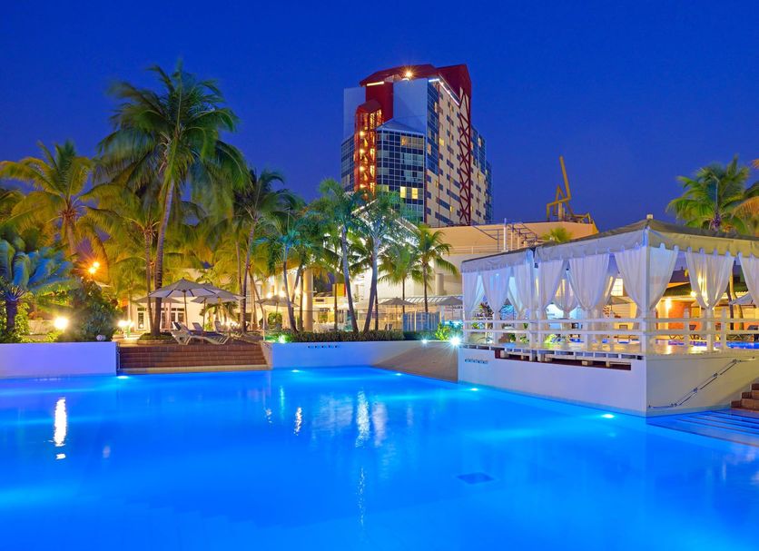 Melia Santiago De Cuba in Santiago de Cuba with a glowing pool, palm trees, and cabana seating at dusk