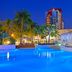 Melia Santiago De Cuba in Santiago de Cuba with a glowing pool, palm trees, and cabana seating at dusk
