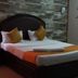 Hotel Meena Paradise, Visakhapatnam: bed with orange runner, pillows, and stone-patterned wall