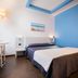 Hotel Mediterraneo in Villa Cortese: compact double room with blue accent wall, bed, and small table