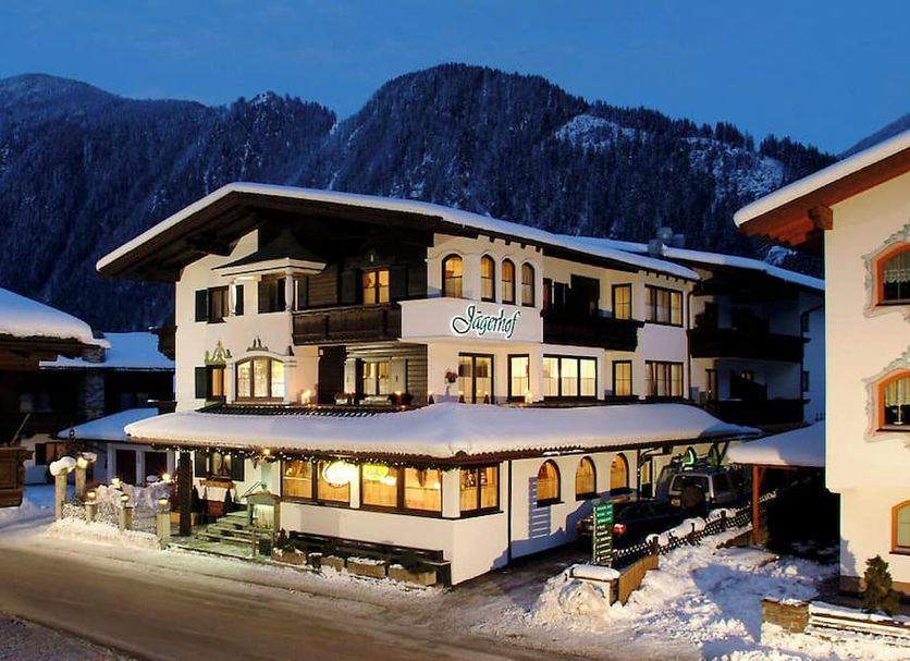 Hotel Jägerhof Mayrhofen in Mayrhofen, snow-covered chalet hotel at dusk with lit windows and mountain backdrop
