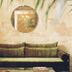 Shila Athens in Athens lounge with velvet sofa, round mirror and potted palm against textured wall