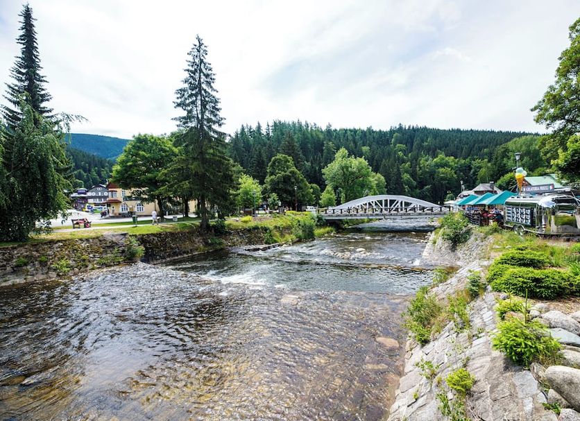 Hotel Jelinek in Špindlerův Mlýn by a river with bridge and forested hillside views