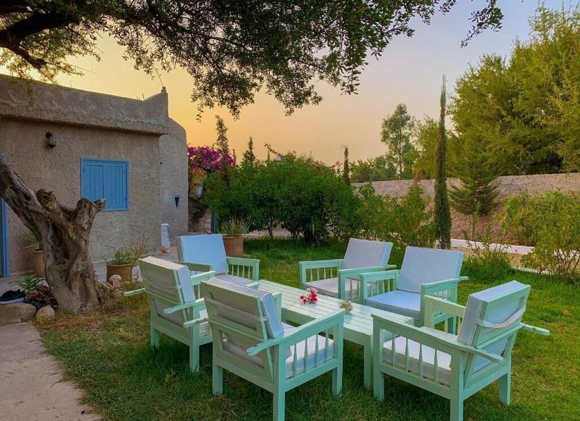 Hotel Riad Tigmin Eden in Essaouira: outdoor garden seating with mint-green chairs and sunset sky