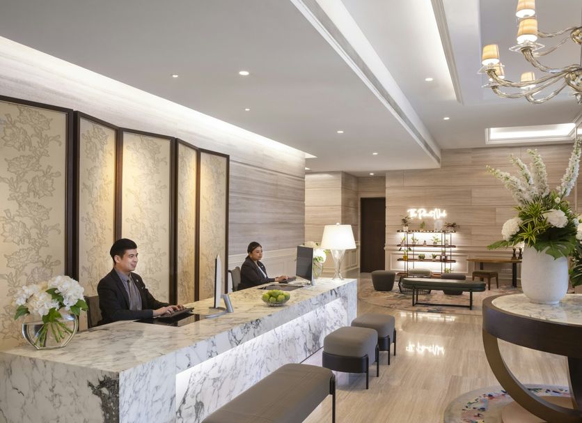 Fraser Suites Singapore lobby with marble front desk, seating, and chandelier lighting