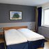 Hotel Göingehof in Hässleholm bedroom with twin beds, framed wall art, and window light
