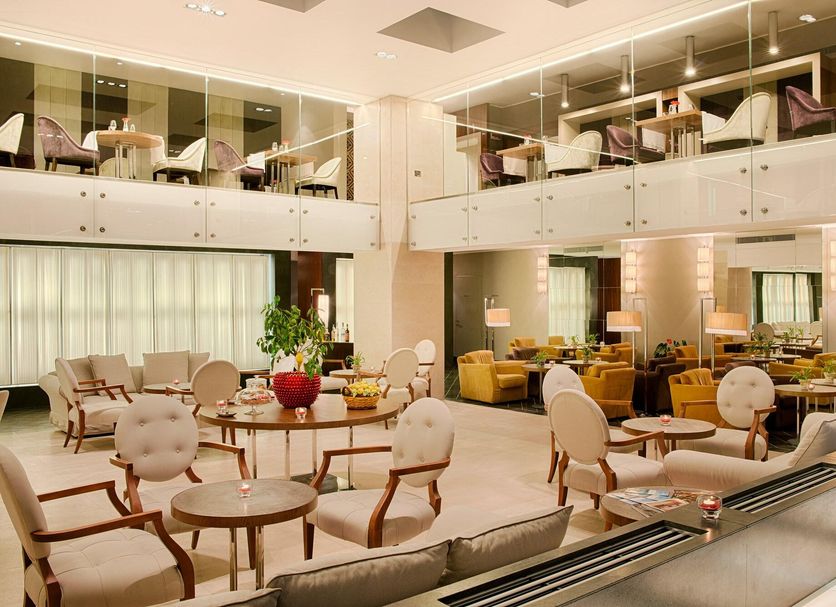 NH Collection Taormina lobby lounge with seating, mezzanine dining area and warm contemporary decor