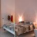 Sfumature Partenopee Naples room with white iron bed, bedside lamps and sofa