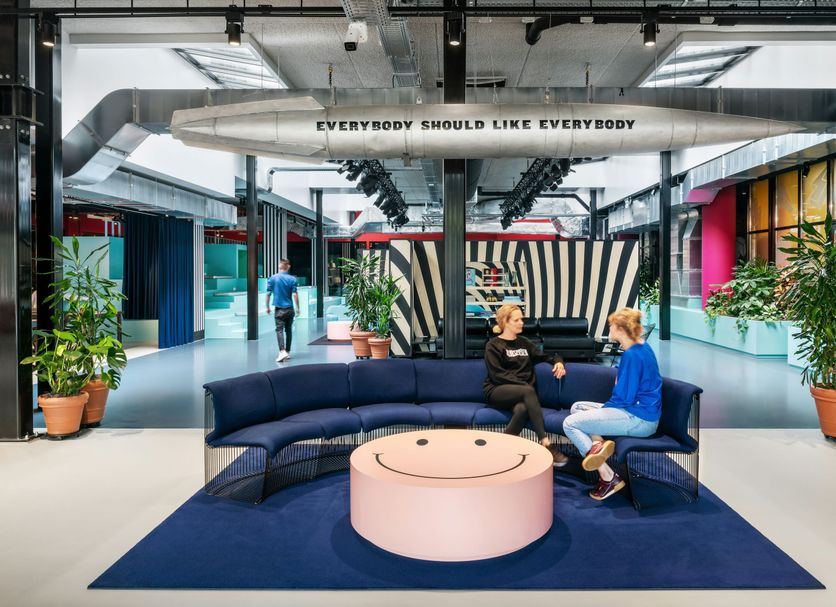 The Social Hub Amsterdam City lobby with curved blue seating, pink round table and industrial design