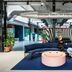The Social Hub Amsterdam City lobby with curved blue seating, pink round table and industrial design