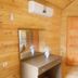 Fire pansiyon in Cirali: wood-paneled guest room with wall AC, dresser mirror, and wooden door