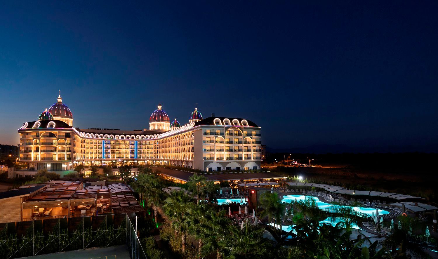Adalya Elite Lara Hotel in Antalya at night with illuminated facade and outdoor pools