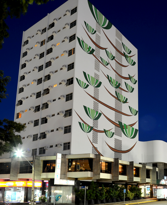 Copas Verdes Hotel in Cascavel, exterior at night with tall painted facade and ground-level shops
