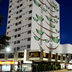 Copas Verdes Hotel in Cascavel, exterior at night with tall painted facade and ground-level shops