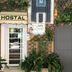 Hostal Tres Cantos entrance in Tres Cantos with hostal sign, white door and leafy potted plants