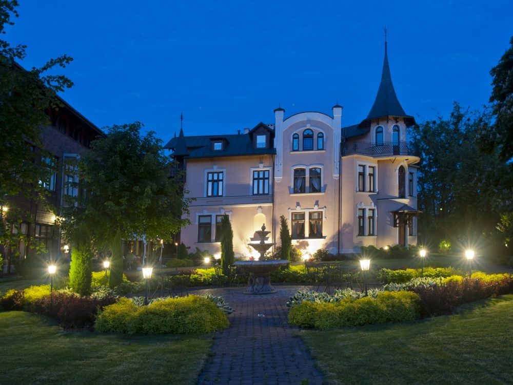 Pensjonat Pod Jemiola in Ciechocinek at dusk, lit garden and elegant multi-story facade