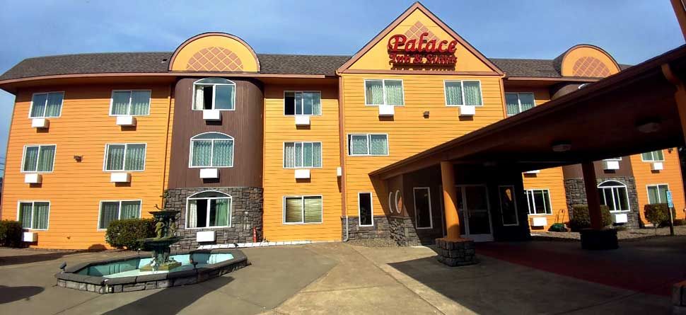 Palace Inn & Suites in Lincoln City with orange exterior, covered entrance, and outdoor seating