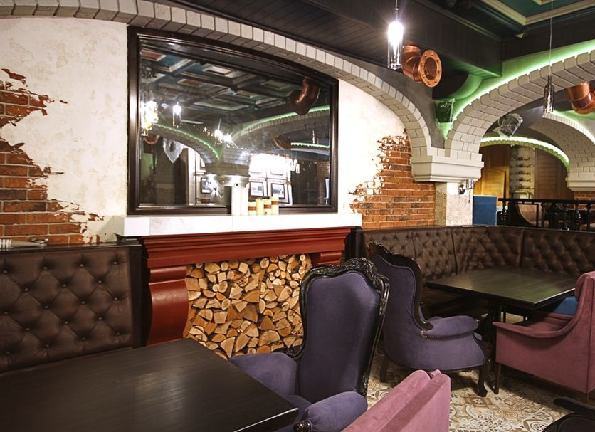 City Park Hotel, Chisinau lounge with tufted seating, exposed brick arches and wood stack decor