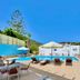 Venardos Hotel in Agia Pelagia with outdoor pool, sun loungers and terrace seating under blue sky