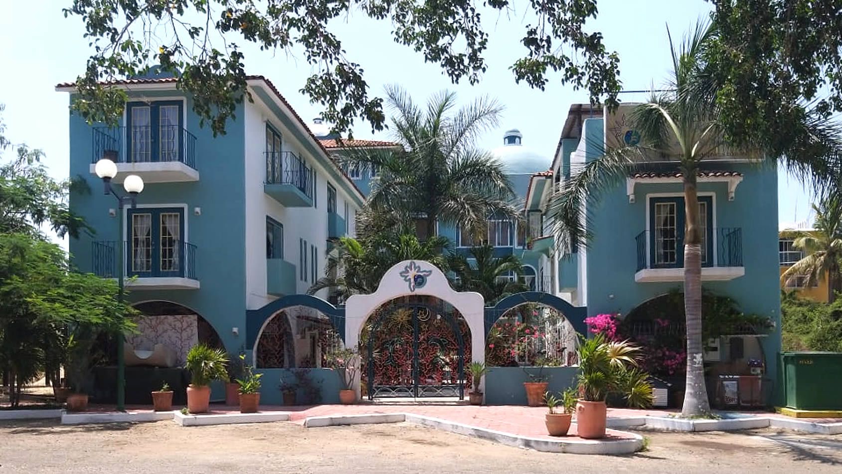 Hotel Delphinus Inn in La Crucecita with tropical courtyard, arched entry, palm trees and colorful buildings