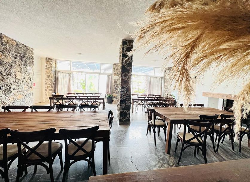 Hotel Grand Vista Cuernavaca in Cuernavaca dining room with wooden tables, black chairs and stone columns