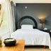 Hotel Grand Vista Cuernavaca room with white bed, dark accent wall, bedside lamp, and wood table