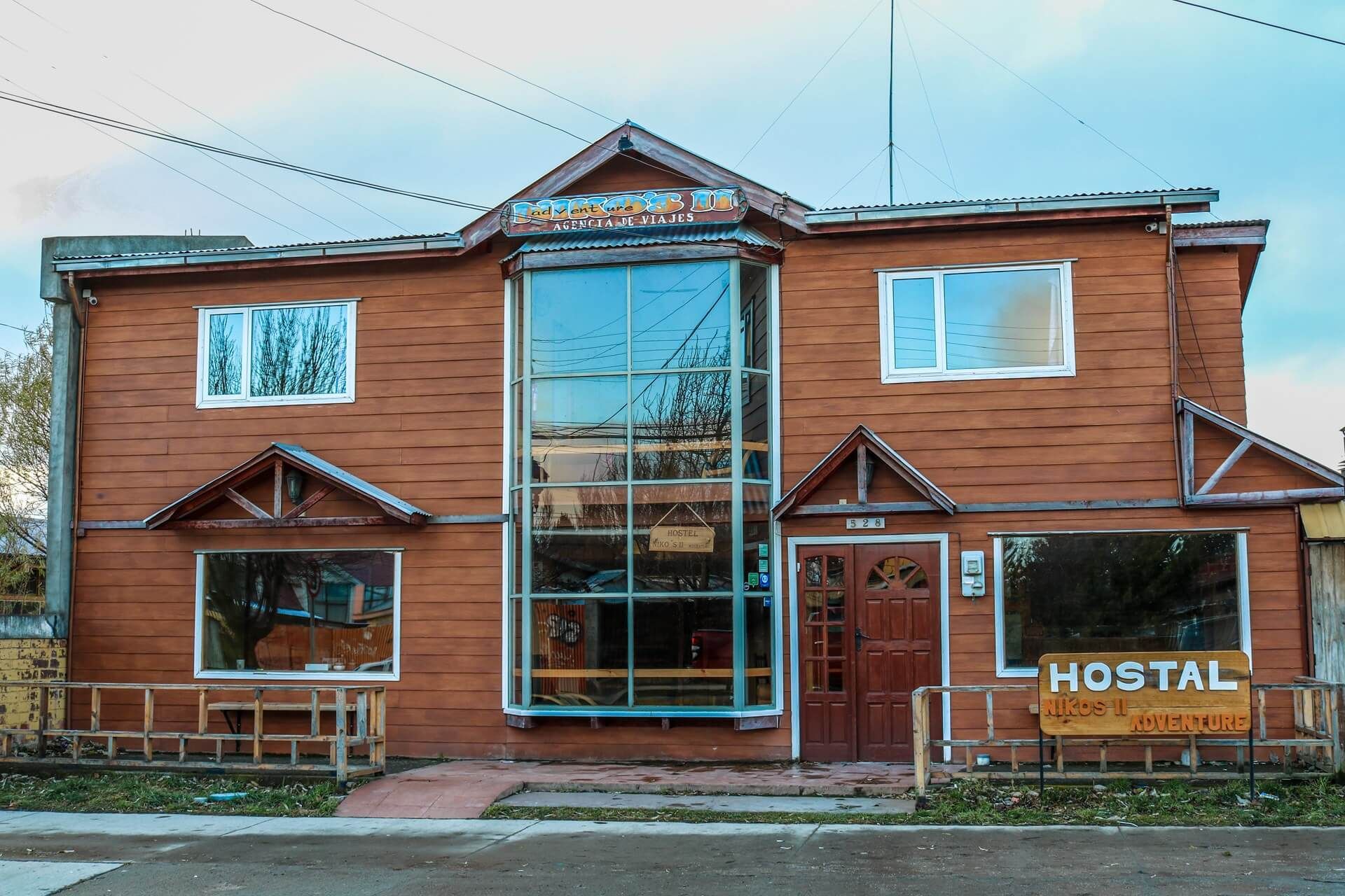 Nikos II Adventure in Puerto Natales, wooden hostel exterior with large central glass entrance