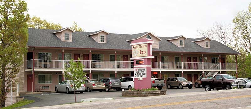 Apple Blossom Inn in Eureka Springs exterior with balconies, parked cars, and roadside sign