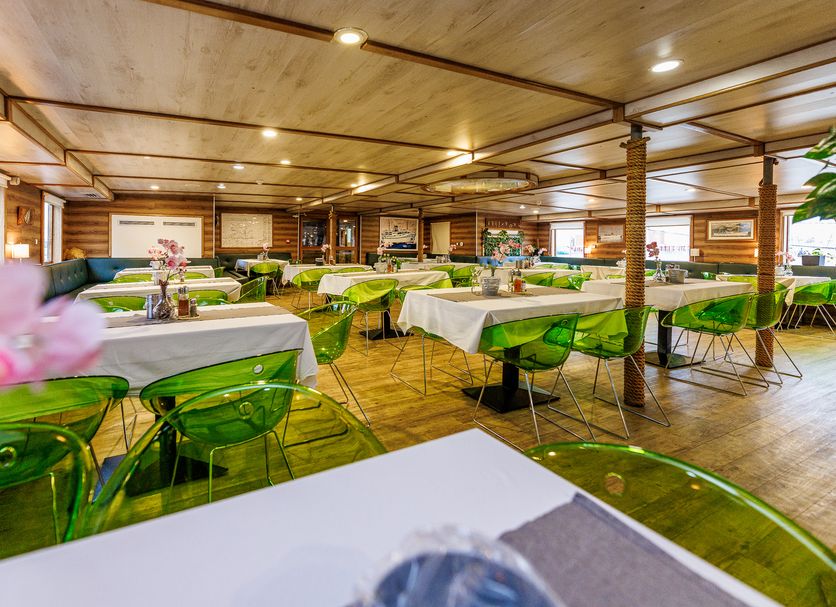 Botel Marina in Rijeka dining room with green chairs, white tablecloths and wood-paneled ceiling