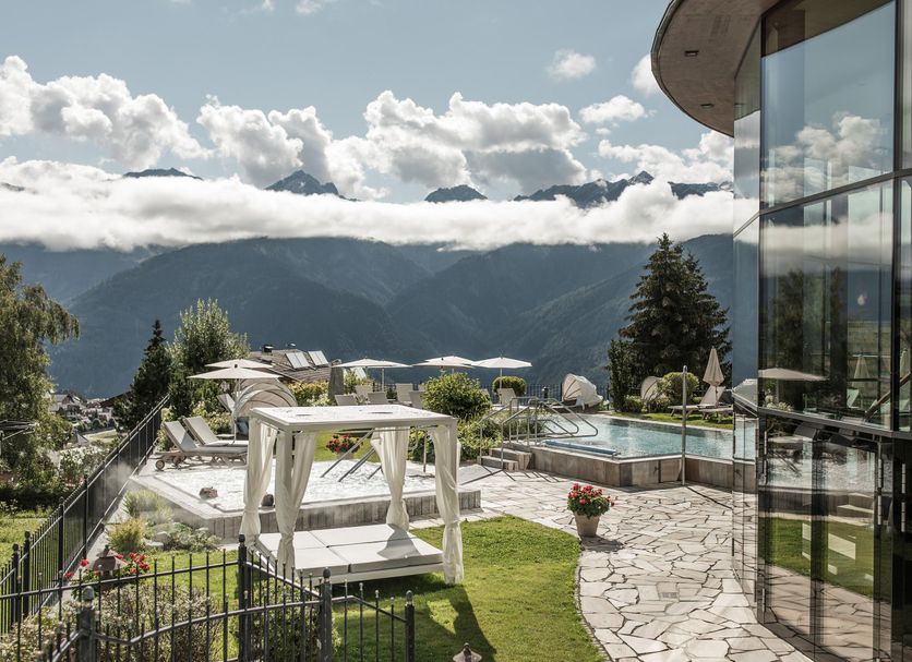 Schlosshotel Fiss in Fiss with mountain views, a terrace, cabana, and outdoor pool beside glass walls