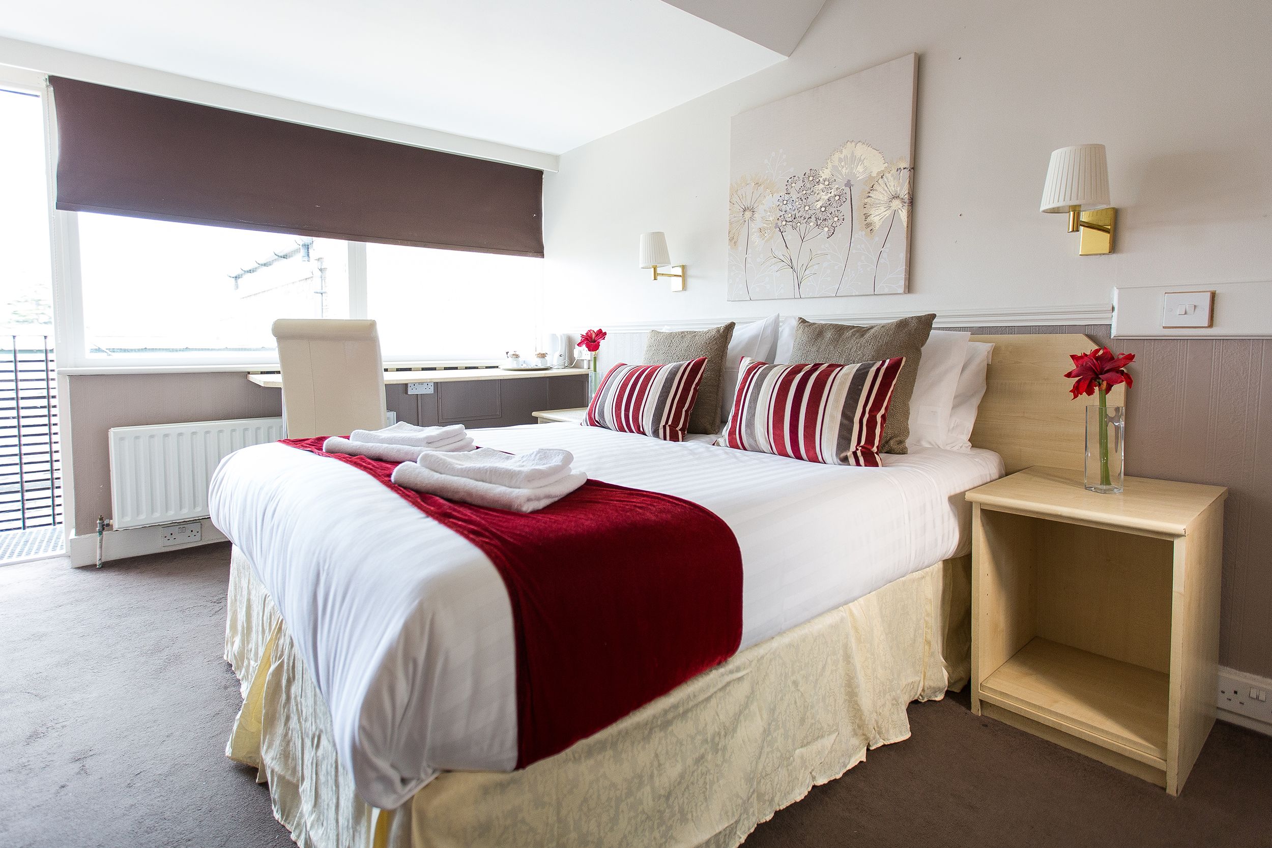 Holtwhites Hotel in Enfield guest room with double bed, red accents, and a window-side desk