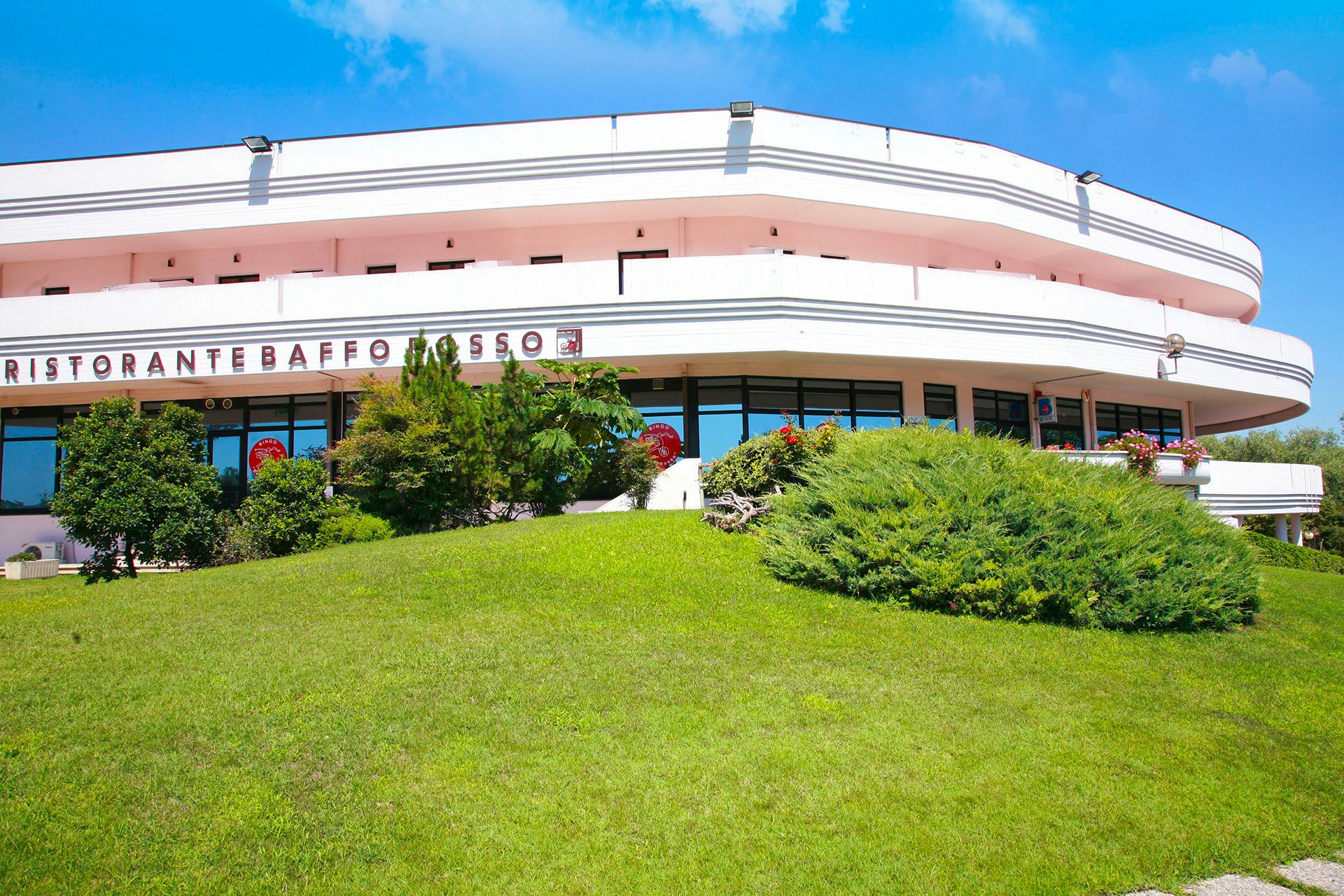 Hotel Baffo Rosso in Corropoli with a curved white exterior and green landscaped lawn