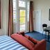 Crashpalace Napier room with stained-glass door, striped sofa, and small table by the window
