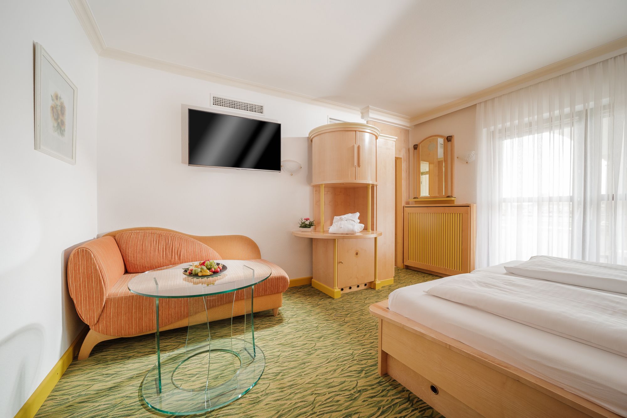 Das-Schmidt Privathotel in Mörbisch am See room with sofa, TV, bed and sheer curtains