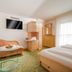 Das-Schmidt Privathotel in Mörbisch am See room with sofa, TV, bed and sheer curtains