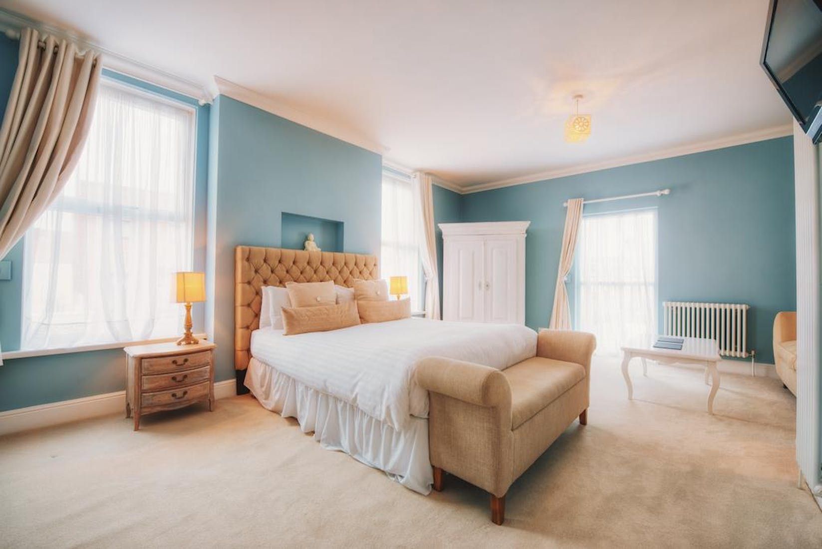 Somerset House Boutique Hotel and Restaurant room in Southsea with tufted bed, blue walls, and tall windows