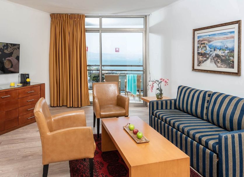 Leonardo Hotel Tiberias room with striped sofa, leather chairs and balcony sea view in Tiberias