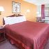 Sunrise Extended Stay in Searcy room with king bed, desk, chair, window and floor lamp.