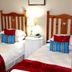Blommenberg Guest House in Clanwilliam, twin bedroom with wooden headboards, bedside lamp and red throws.