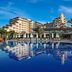 Bellis Deluxe Hotel in Belek with a large outdoor pool reflecting the hotel and palm trees