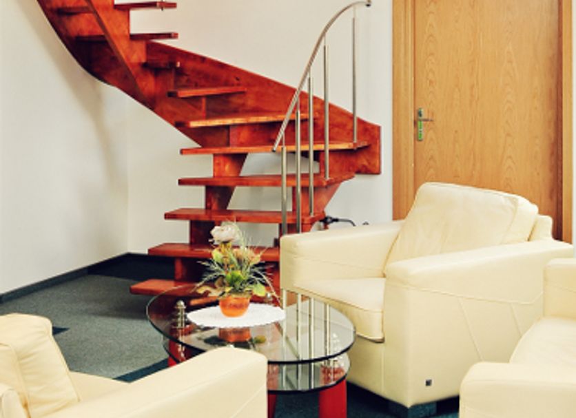Hotel Sanvit Restauracja & Spa lounge with curved wooden staircase, cream armchairs and glass coffee table in Sanok