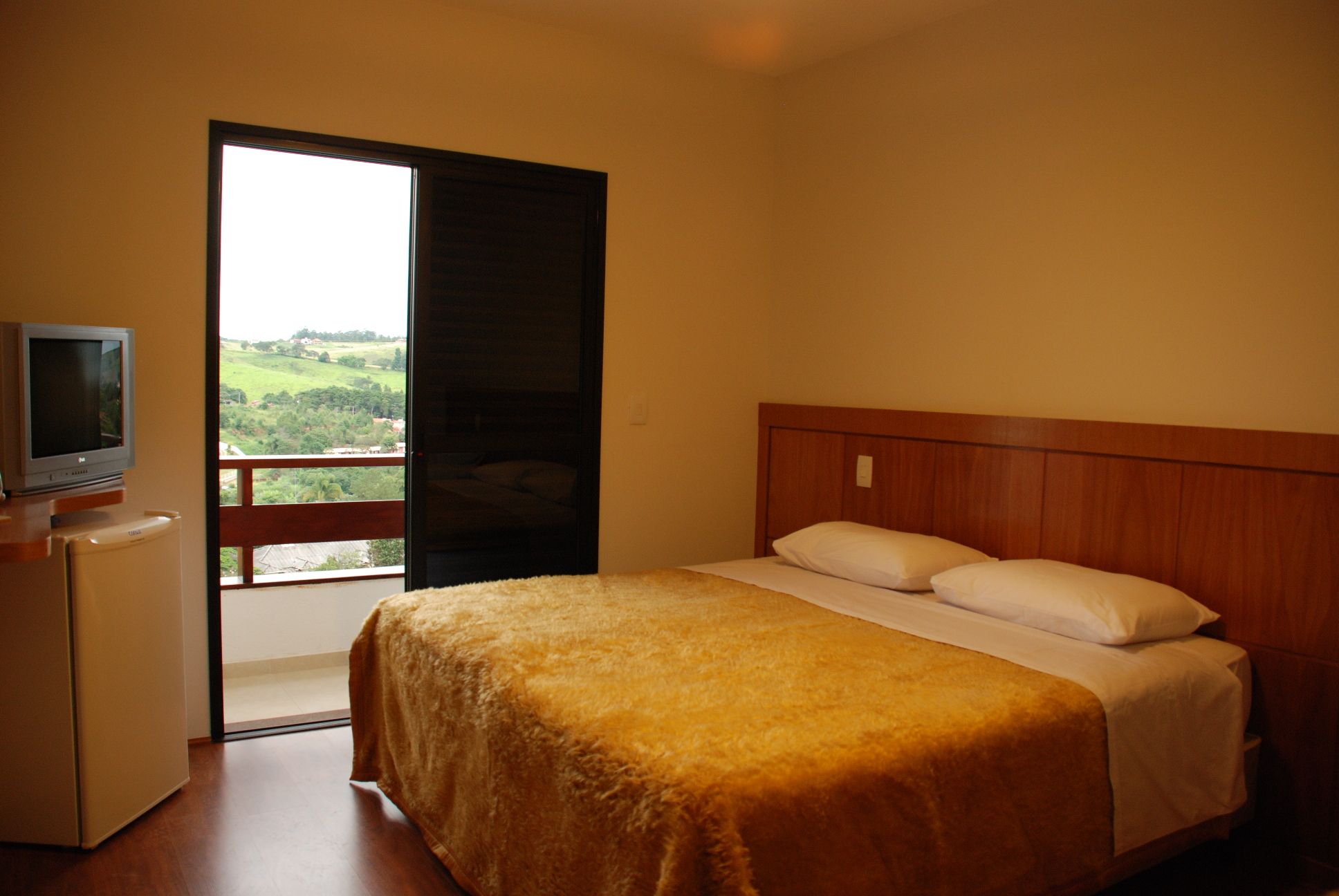 Piemonte Flat Serra Negra Sp room with bed, balcony door, and countryside view in Serra Negra