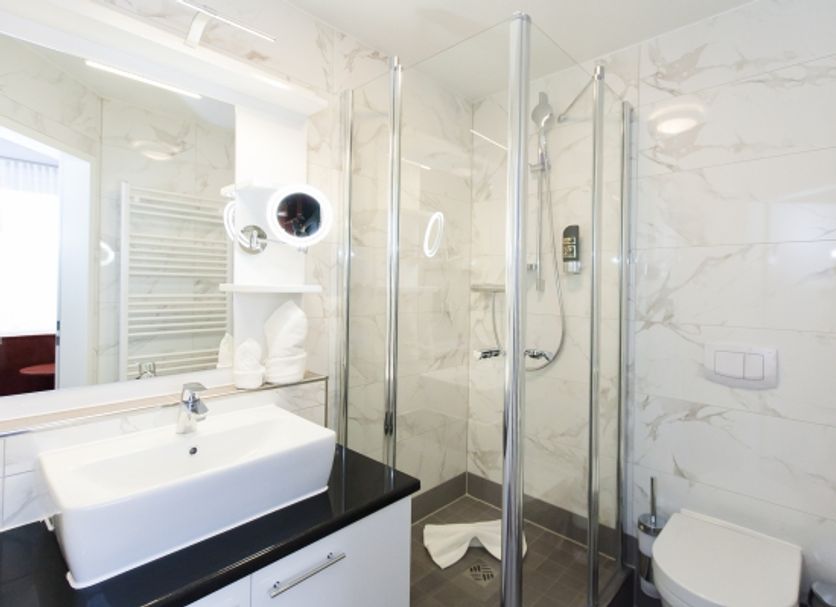 Hotel am Berliner Platz in Langenfeld bathroom with glass shower, sink and toilet