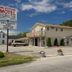 Milestone Motel in Collingwood with roadside sign, parking lot, and two-story exterior under blue sky