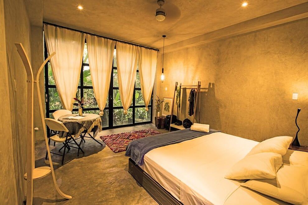 Kapievi Ecovillage in Puerto Maldonado, bedroom with bed, seating area, and large window curtains