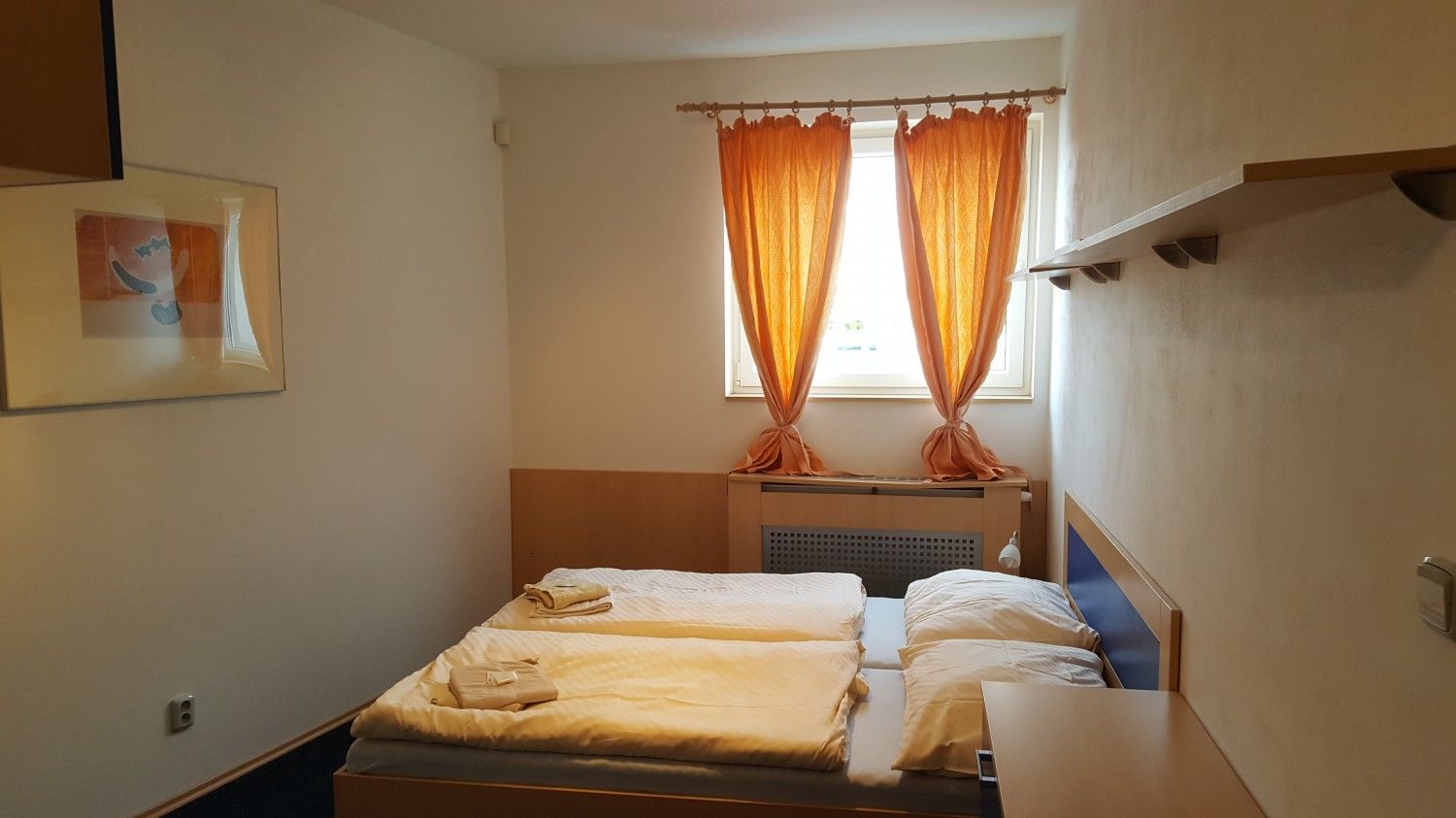 Sporthotel Vestec room with twin beds, orange curtains, and a small window in Vestec