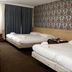 Hotel 74 Amsterdam room with two beds, patterned wallpaper, and window with curtains